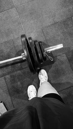 a person standing next to a barbell with their feet propped up on the ground