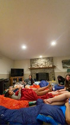 a group of people laying on top of a bed in a living room next to a fire place