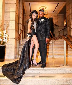 a man and woman standing on the steps in front of some stairs wearing black outfits