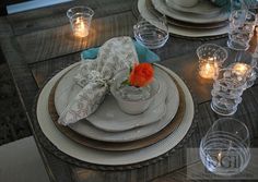 a table set with candles and dishes for dinner