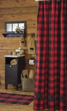 a red and black checkered shower curtain next to a toilet in a bathroom with wood walls