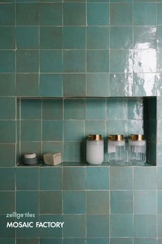 three jars are sitting on the shelf in front of a green tiled wall with gold trim