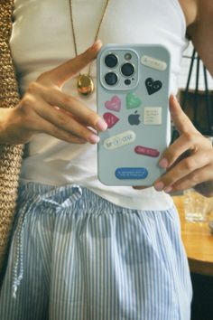 a woman holding up a cell phone case with stickers on it's side