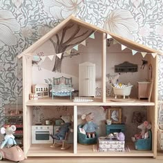 a doll house with furniture and accessories on the floor in front of a wallpapered background