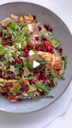 a bowl filled with vegetables and meat on top of a white table next to a fork