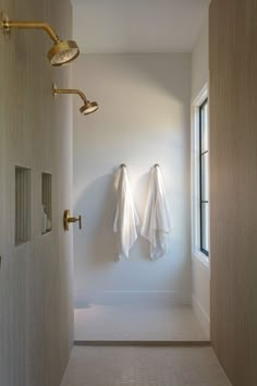 two white towels hanging on the wall next to a window