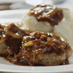 two meatballs covered in gravy on a plate with mashed potatoes