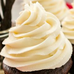 two chocolate cupcakes with white frosting on top are sitting next to each other