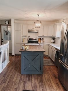 a kitchen with white cabinets and an island that has a wooden counter top in it