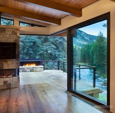 an open living room with a fireplace and large glass doors that look out onto the mountains