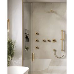 a white bath tub sitting next to a shower with gold fixtures on the wall and floor