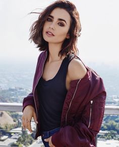 a woman standing on top of a roof with her hands in her pockets and looking off into the distance