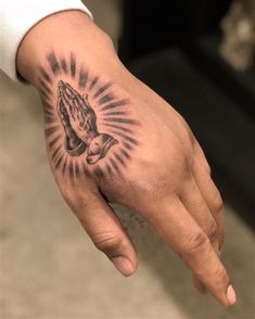 a person's hand with a tattoo on it and a praying hand in the middle