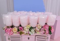 a bunch of pink candles sitting on top of a dresser covered in flowers and plastic bags