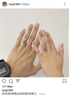 two hands holding each other with small tattoos on their fingers and one hand above the other