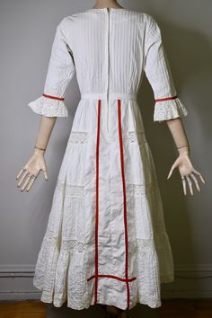 "This dress is so special. It is a vintage 60s/70s Mexican pin tucked white dress. The dress has a square neckline, that is trimmed with red ribbon and small lace ruffles, is fitted to the waist with a floral embroidered bodice that is also finished on the side with red ribbon, it has 3/4 sleeves with a flared lace cuff and red ribbon trim, The skirt is a long maxi skirt that is quite full, it has a front and back center panel with red ribbon running down the length, coming off the front panel i White Victorian Empire Waist Dress, White Cotton Prairie Dress For Wedding, White Broderie Anglaise Regency Dress, White Regency Broderie Anglaise Dresses, White Regency Style Broderie Anglaise Dresses, White Broderie Anglaise Victorian Wedding Dress, White Victorian Dress For Garden Party, White Victorian Wedding Dress With Broderie Anglaise, White Victorian Wedding Dress For Summer