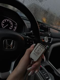 a woman holding a remote control in her hand while driving a car on a rainy day