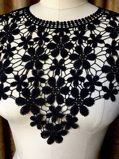 a black crocheted neck piece on a mannequin's torso is shown