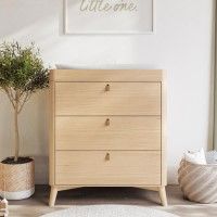 there is a small wooden dresser next to a potted plant