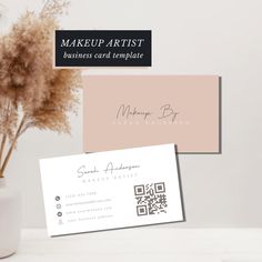 two business cards sitting on top of a table next to a vase filled with flowers