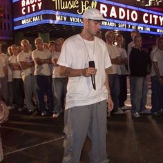 a man is standing in front of a crowd with headphones on and holding a microphone