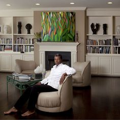 a man sitting on a chair in front of a fire place and bookshelves