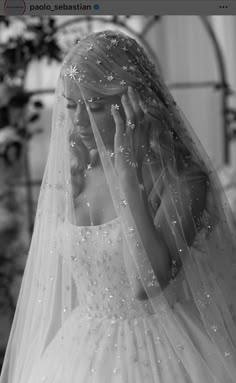 a woman in a wedding dress holding her hands to her face while wearing a veil