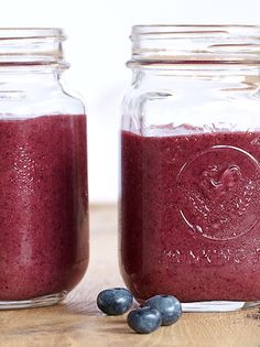 two mason jars filled with blueberries on top of a wooden table next to each other