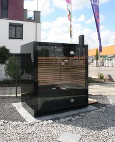 a large black box sitting on top of a gravel field next to a tall building