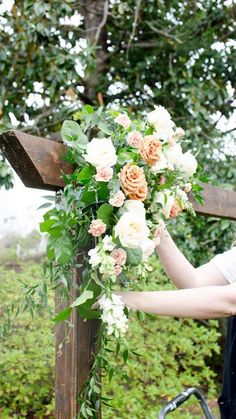 a woman holding a bouquet of flowers on top of a wooden cross