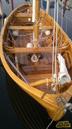 a wooden boat docked at a dock with ropes on the front and side of it