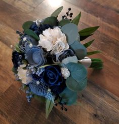 a bridal bouquet with blue and white flowers on a wooden floor in a room