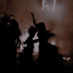 silhouettes of people dancing in front of a fire