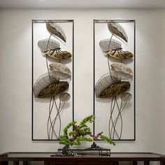 two metal wall sculptures with leaves on them in a living room next to a table