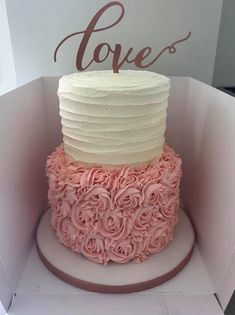 a pink and white cake in a box with the word love on it's top