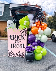 a trunk or treat sign surrounded by balloons and halloween decorations in front of a car