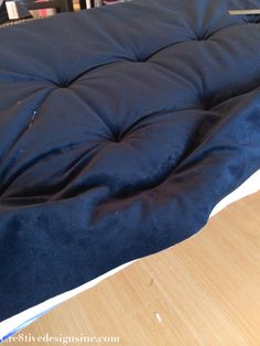 an unmade bed sitting on top of a wooden floor next to bookshelves