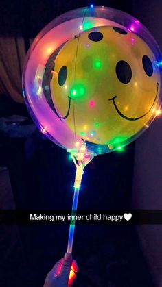 a person holding a smiley face balloon with lights on it