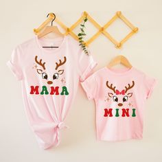 Holiday Fashion Clothing ON SALE Welcome the most wonderful time of the year, Christmas, in these very cute retro matching Mommy and Me Mama Mini Christmas reindeer shirts.  Celebrate the holidays with family and friends and have a very merry Christmas in these shirts. We use the softest, lightest and most comfortable shirt available, the Bella Canvas 3001.  It's everyone's favorite tshirt.  This classic unisex jersey short sleeve shirt fits like a well-loved favorite. Soft cotton and quality print make users fall in love with it over and over again. These t-shirts have-ribbed knit collars to bolster shaping. The shoulders have taping for better fit over time. Dual side seams hold the garment's shape for longer.  Since this Bella Canvas 3001 shirt is unisex in size, if you want a tighter f Mom And Me Christmas Outfits, Cute Pink Top For Holiday, Cute Pink Holiday Tops, Cute Pink Holiday Top, Matching Christmas Cotton Tops, Matching Cotton Christmas Tops, Matching Cotton Tops For Christmas, Cute Cotton Holiday Tops, Pink Cotton Christmas Tops