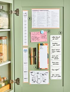 a bulletin board with notes and magnets on it in a green cabinet next to a glass jar