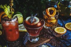 two glasses filled with drinks sitting on top of a wooden table next to sliced lemons