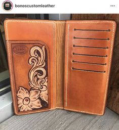 an open brown leather wallet sitting on top of a wooden table next to a window