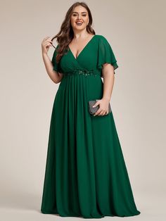 a woman in a long green dress is smiling and holding her hand on her hip