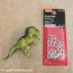 a small toy dinosaur next to a packaged screwdriver