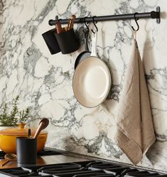 pots and pans are hanging on the wall above the stove in this modern kitchen