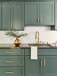 a kitchen with green cabinets and gold pulls on the handles, brass faucet