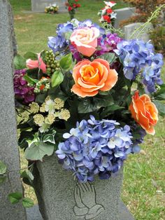 an arrangement of flowers is placed in a stone urn on the cemetery's grave