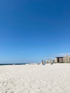 people are on the beach with buildings in the background