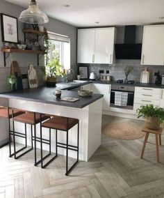 a kitchen with white cabinets and an island in the middle, surrounded by wooden flooring