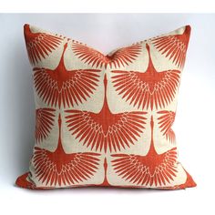 an orange and white pillow with large leaves on the front, against a white background